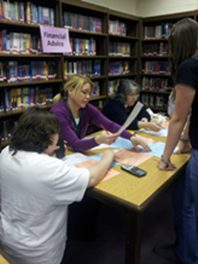 Volunteers help students explore financial concepts during a Real Money, Real World simulation.